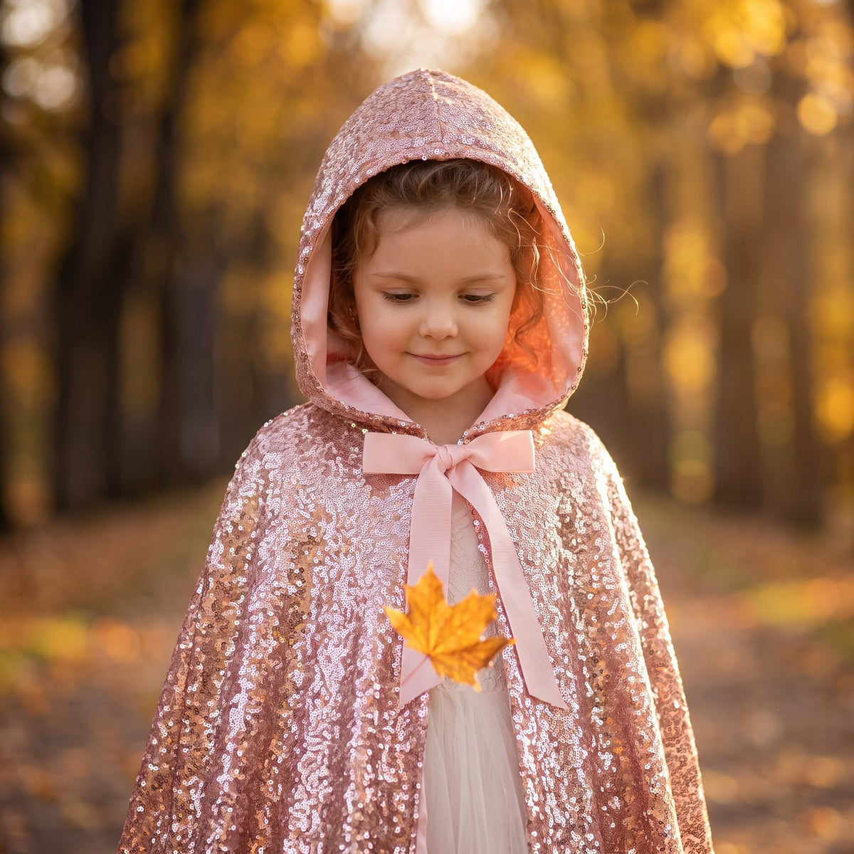 Close up of the hood up and the pink satin ribbon bow on the Rose Gold Sequined Cape