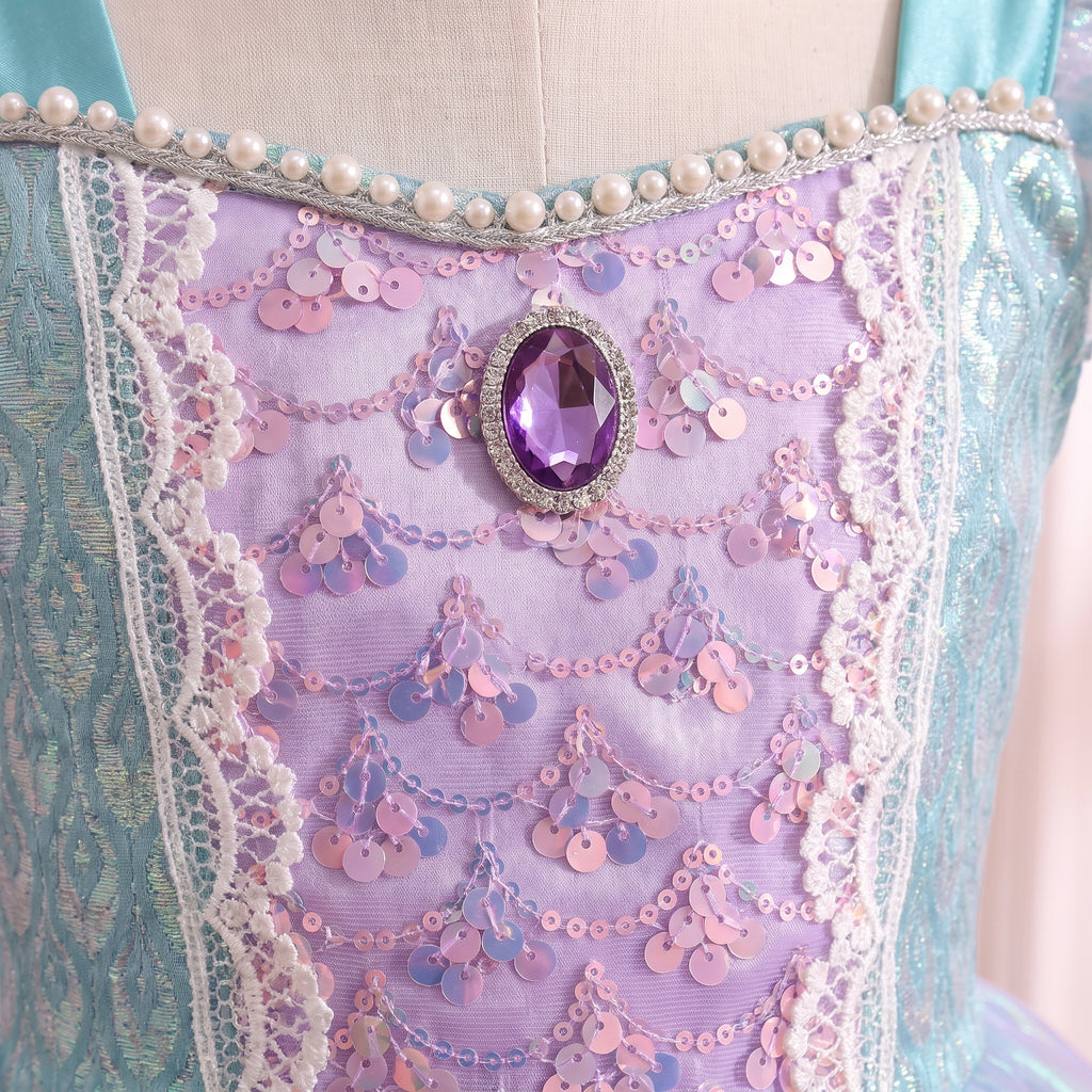 Close up of the mermaid bodice: lilac sequin scallops, pearl-edged neckline and a purple oval jewel in silver filigree