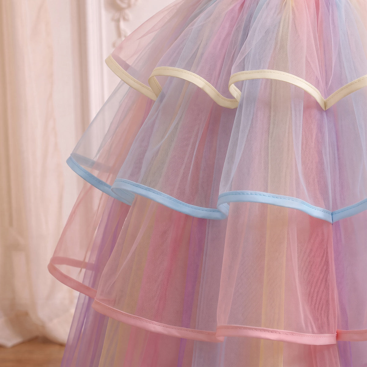 Close up of the three ribbon-edged ruffle tiers in cream, sky blue and pink over rainbow striped tulle