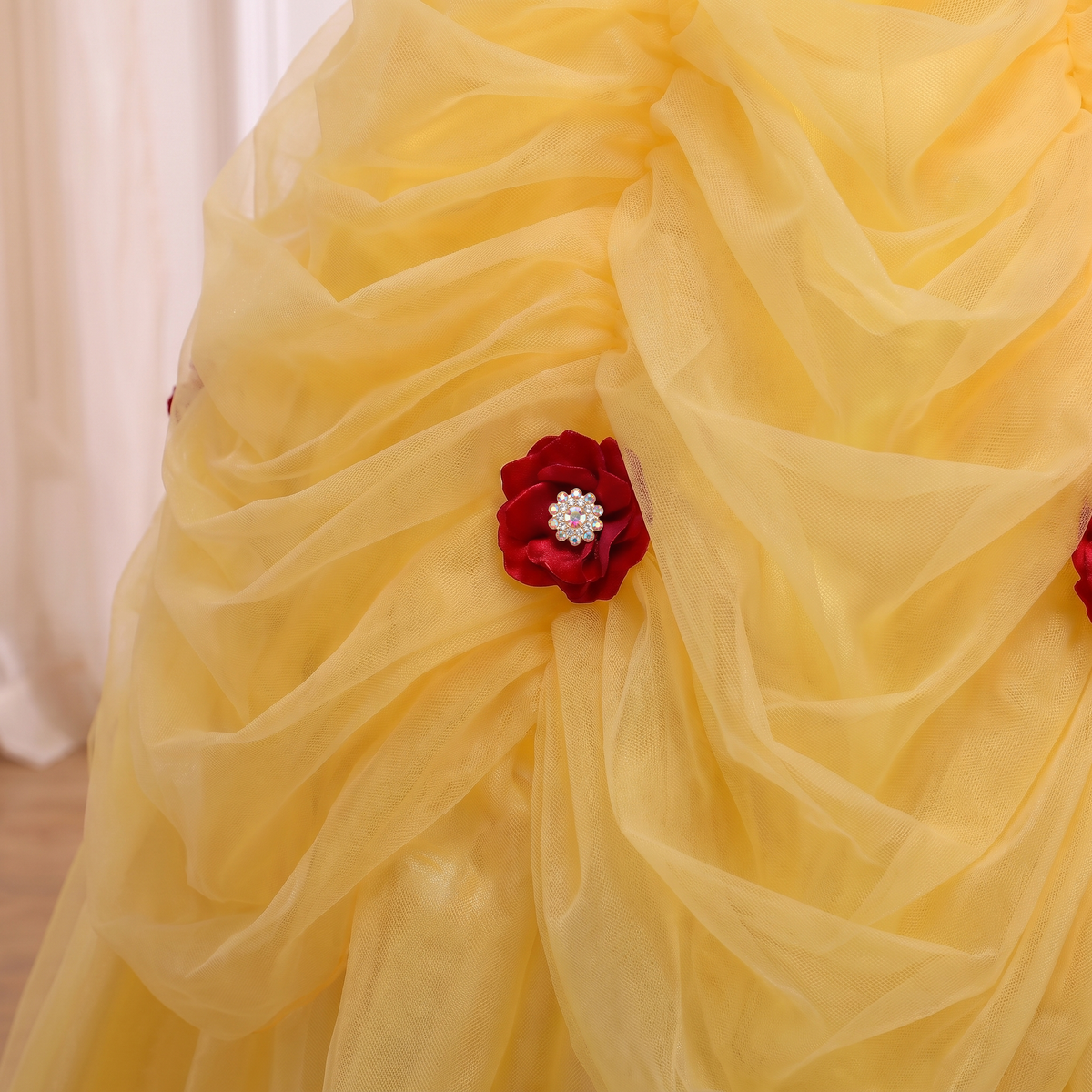 Close up of a crimson rose with a rhinestone center pinned to a tulle swag