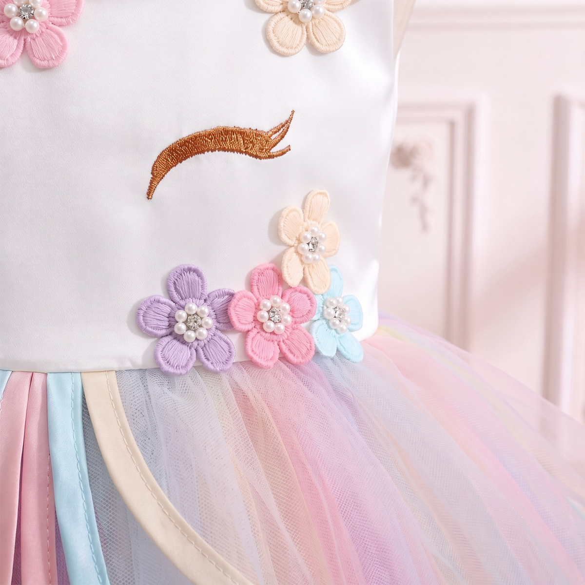 Close up of the golden embroidered lashes and pastel flower crown on the white bodice