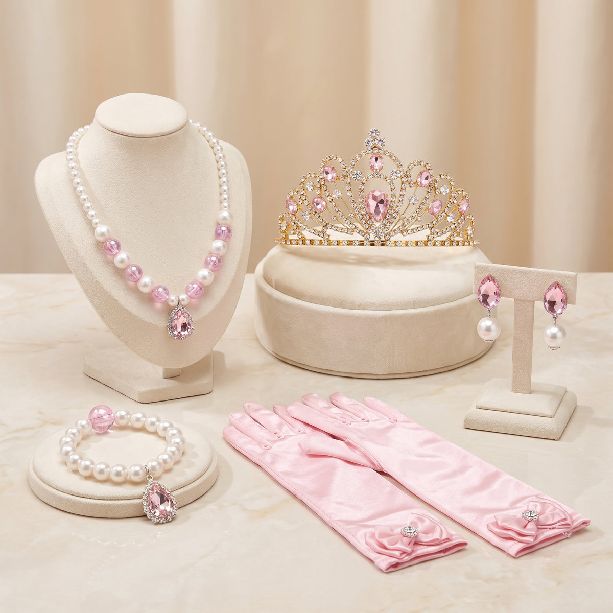 Golden Pink Accessory Set flat lay: pearl necklace, gold-tone tiara with pink stones, pink teardrop clip-on earrings, pearl bracelet and pink satin gloves