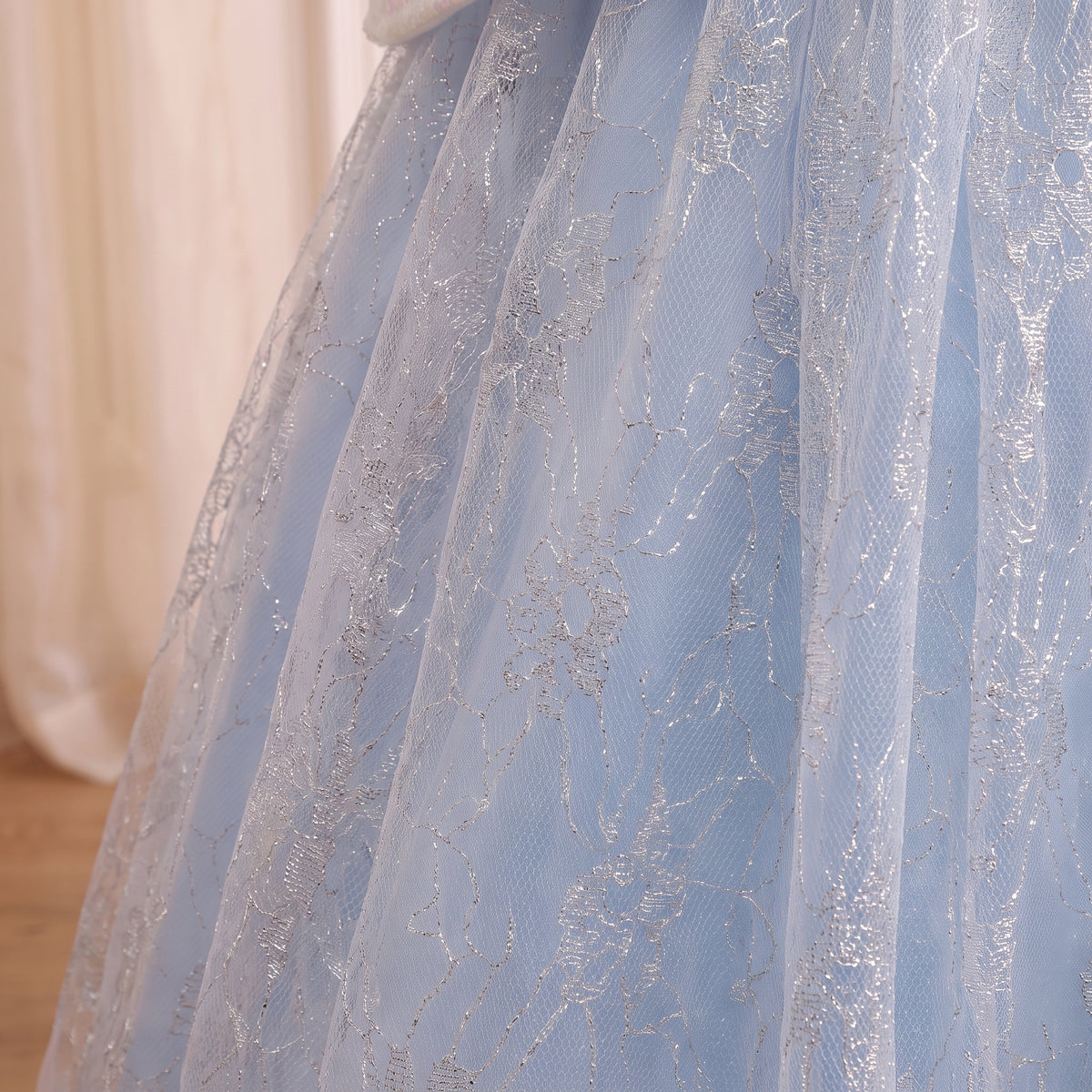 Close up of the silver lace overlay on the pale ice blue ball gown skirt