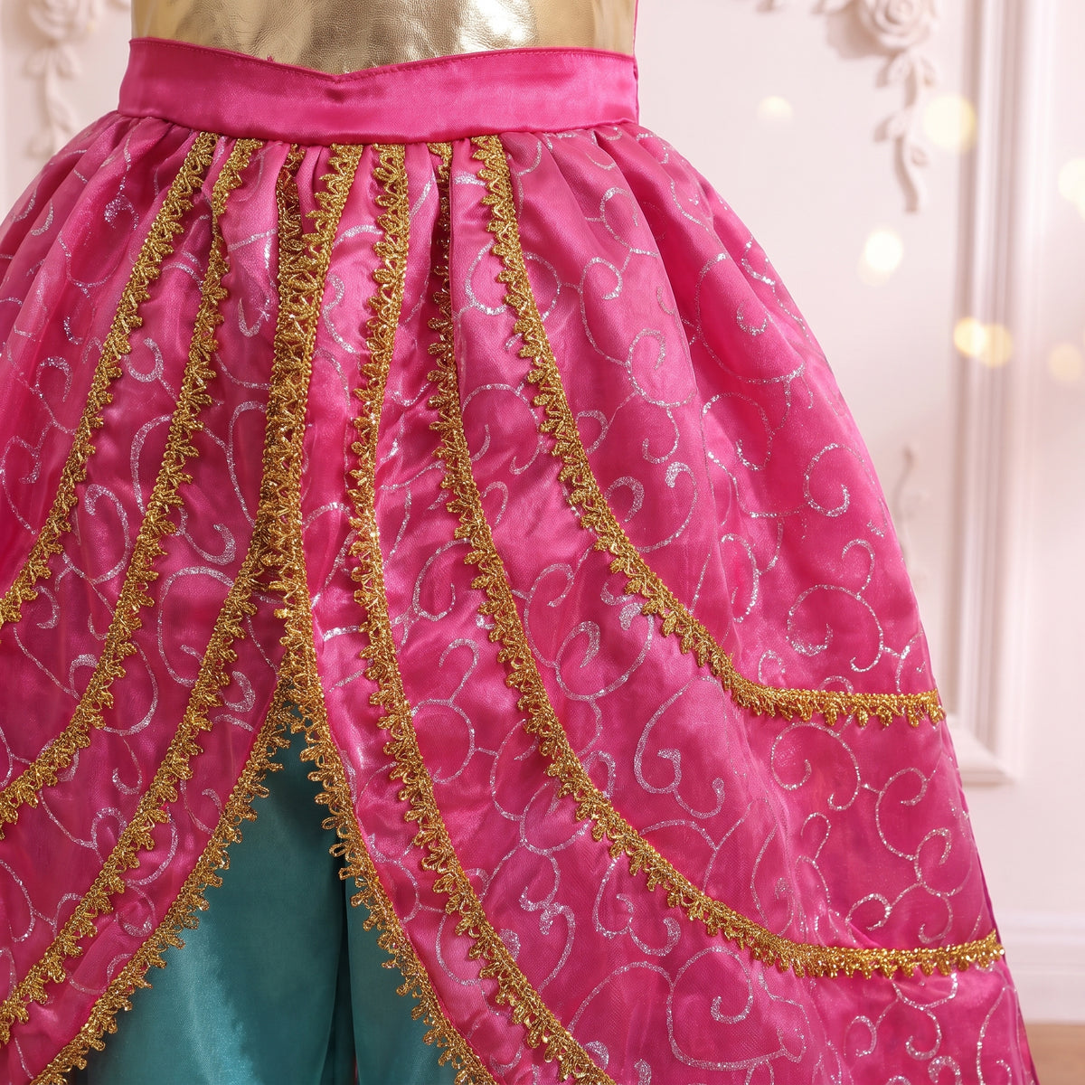 Close up of the gold braid trimmed overskirt tiers opening over the teal satin harem pants