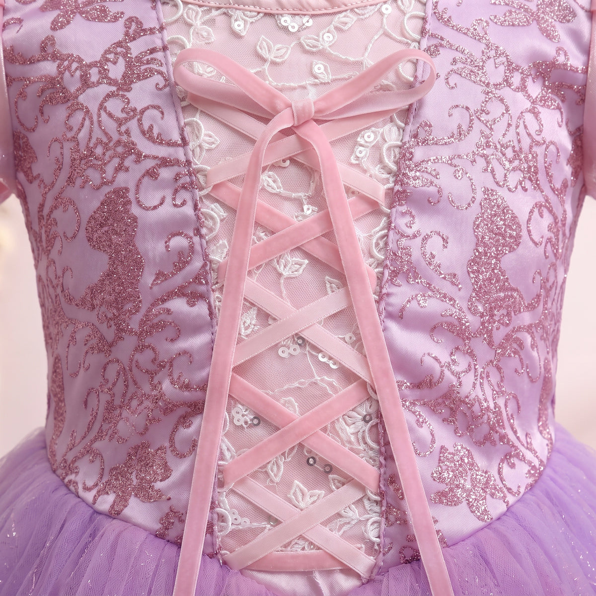 Close up of the Rapunzel bodice: pink ribbon lace-up over a lace inset with magenta glitter scrollwork on each side