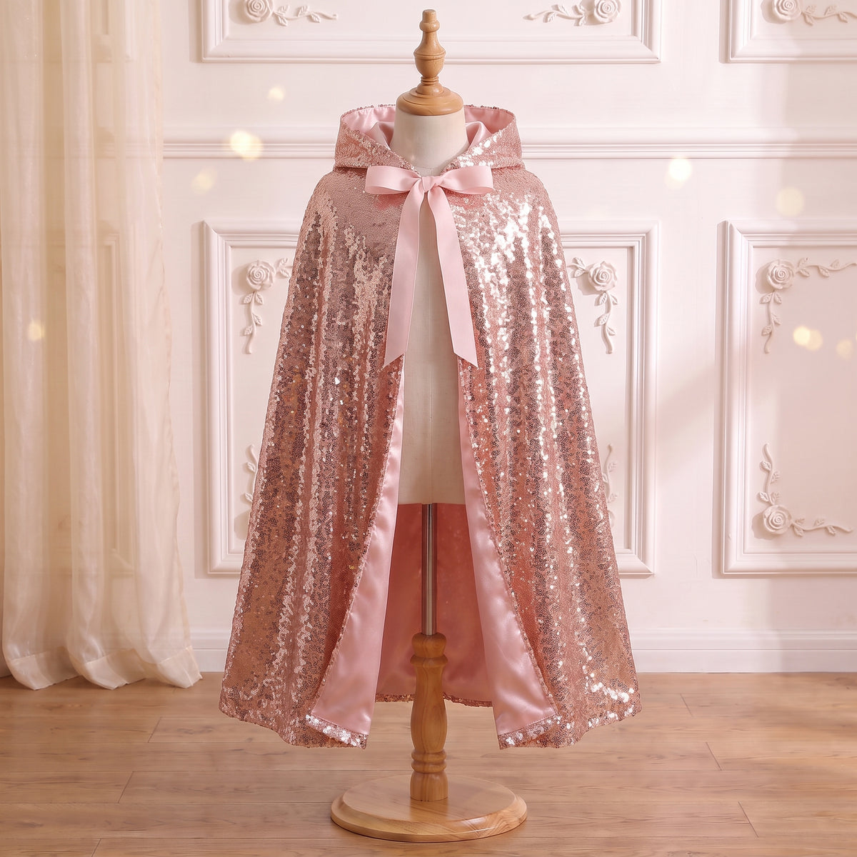 Front view of the Rose Gold Sequined Cape on a mannequin: pink satin lining and ribbon bow