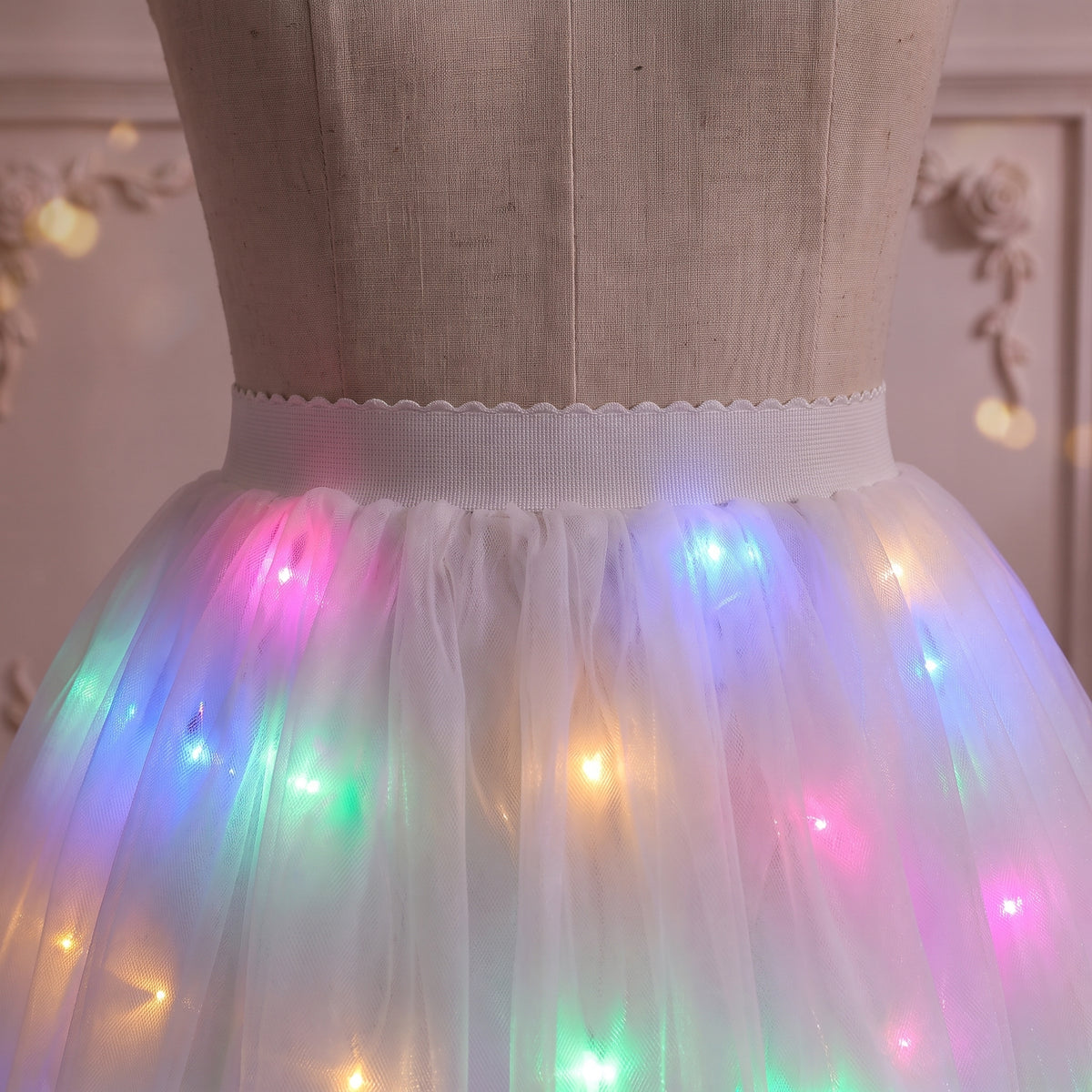 Close up of the scalloped white waistband and multicolor lights through the tulle