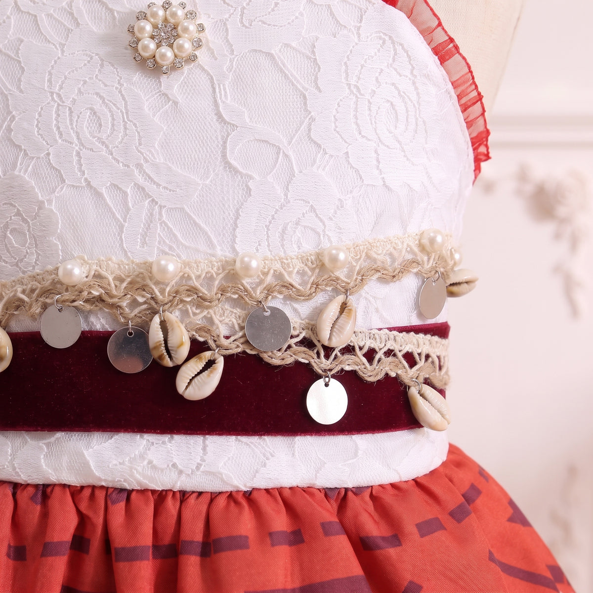 Close up of the burgundy velvet belt with cowrie shells, shell coins, and pearl crochet braid