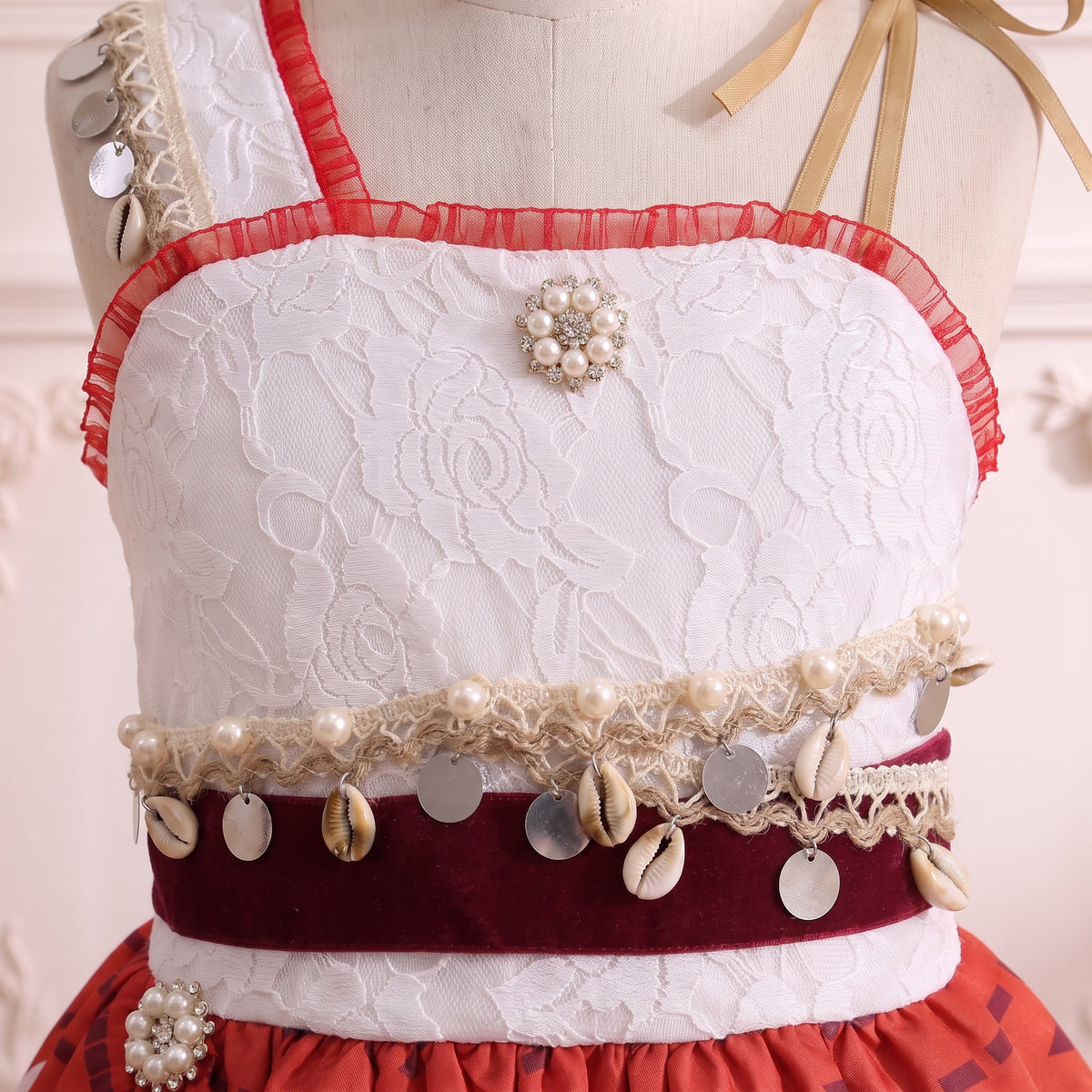 Close up of the white rose lace bodice with pearl and crystal flower brooch and crimson organza ruffle trim