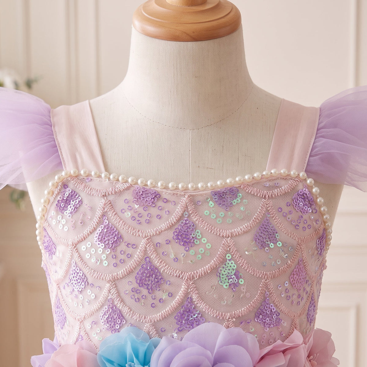 Close-up of scale-pattern sequins, pearl-style trim and lavender flutter sleeves